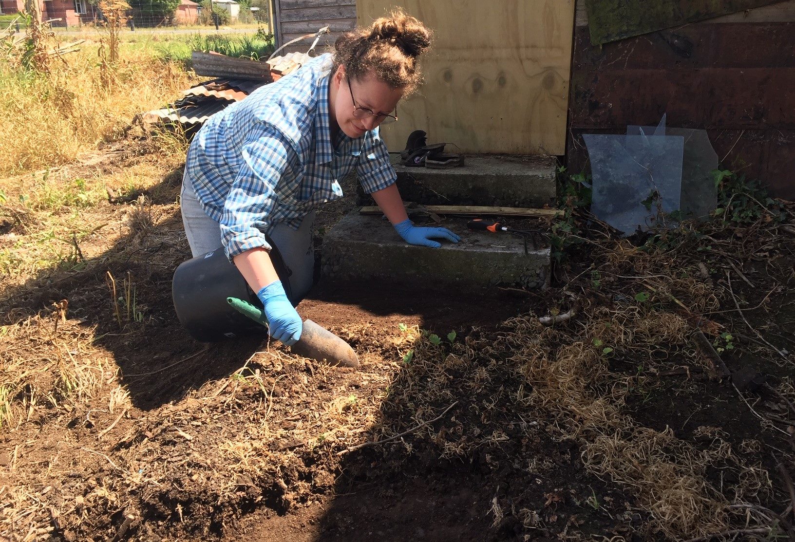 Archaeologist Gwen Hoopmann uncovering a former concrete path behind the living area at the Ng King Bros. Chinese Market Garden Settlement, February 2022. Courtesy of Arlene Baird.