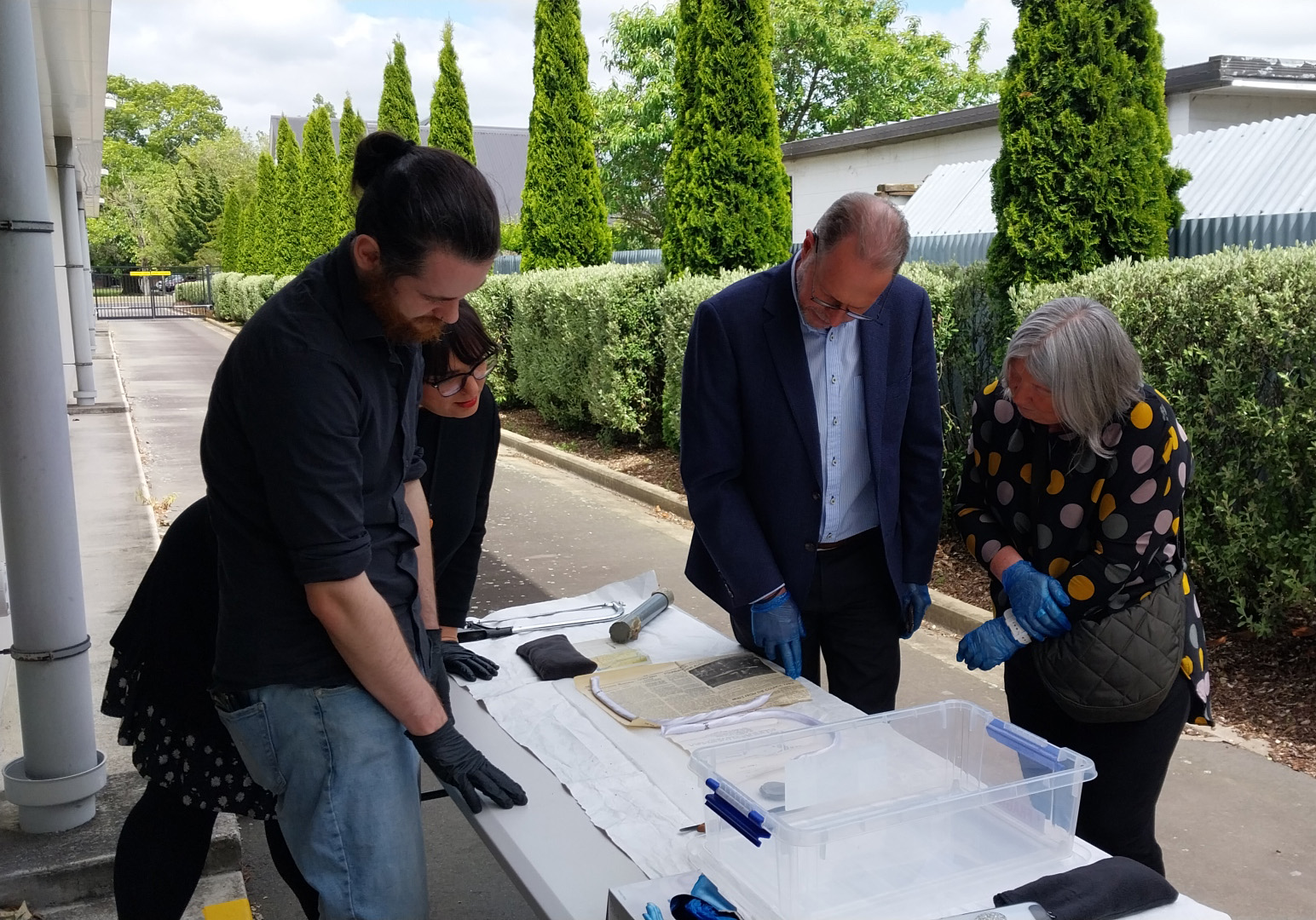 Four people looking at items on table