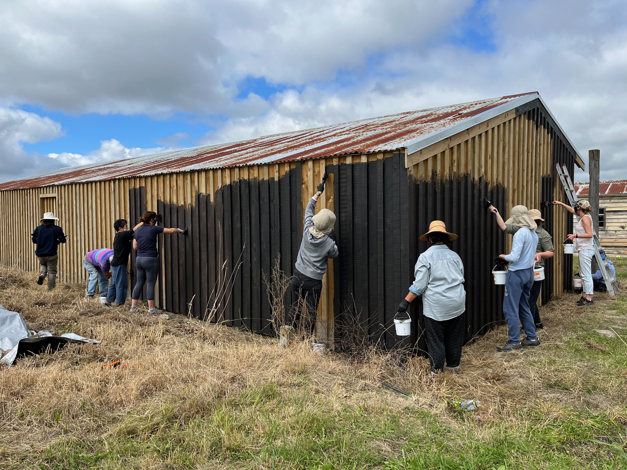 Volunteers painting the former garages, used for storing carts and later trucks, at the Ng King Bros. Chinese Market Garden Settlement, February, 2022. Courtesy of Arlene Baird.